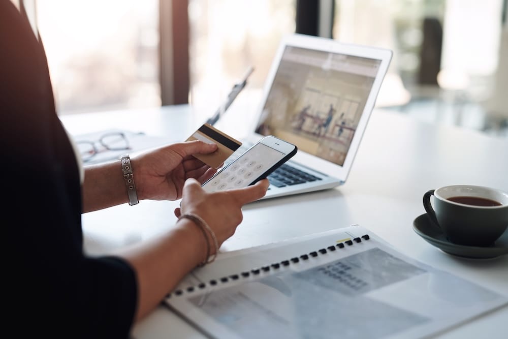 Fintech professional managing a digital payment card program on a tablet and laptop