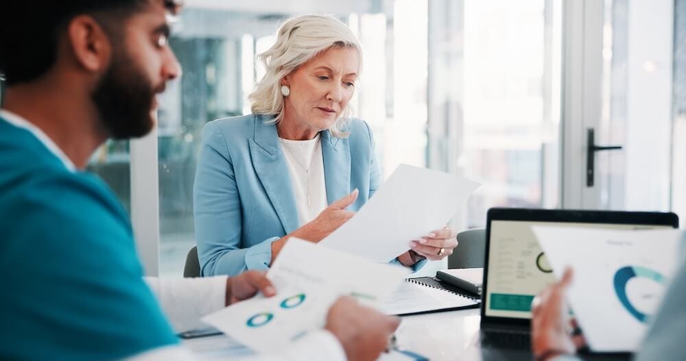 Professionals reviewing payment card program documents during an organizational planning meeting